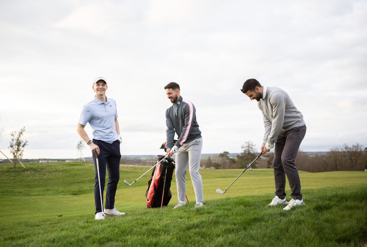 Trois joueurs sur le parcours du Golf du Liberty Country Club, prêts à jouer leur approche